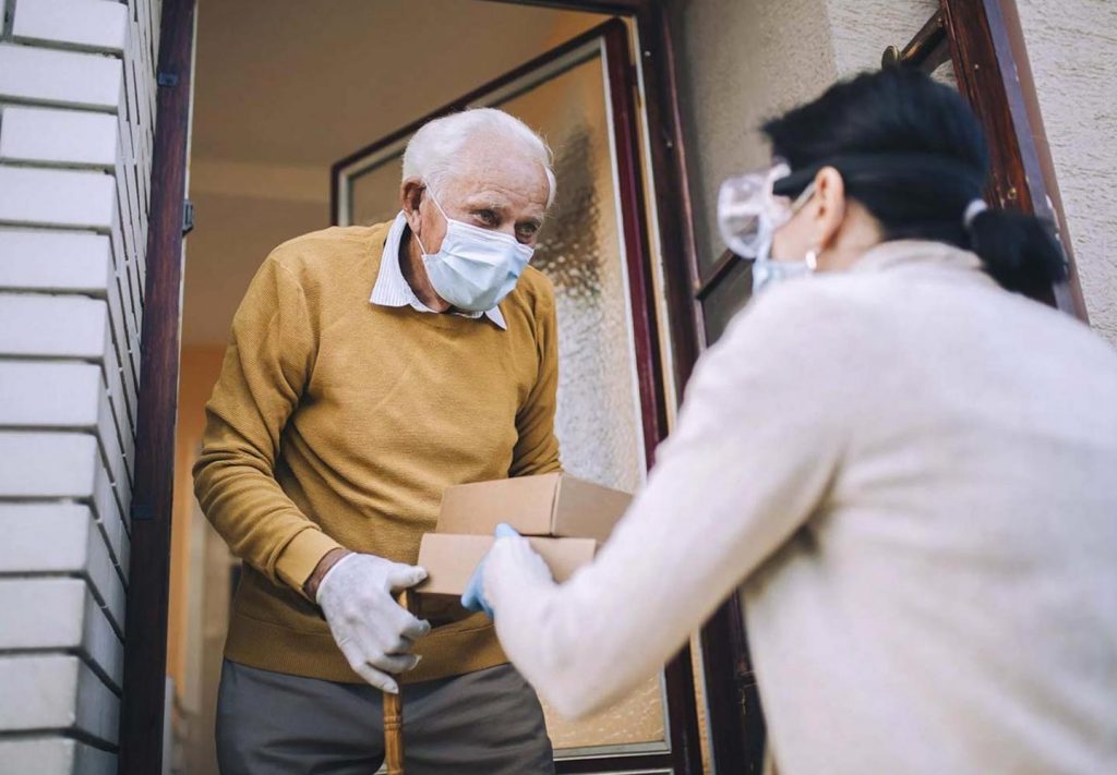 Older gentleman receiving supplies from woman at front door